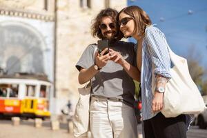 Smiling traveler couple standing on old city street background and use smartphone photo