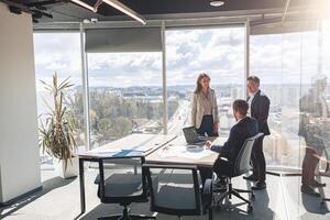 Team of young businessmen working and communicating together in office with panoramic windows photo