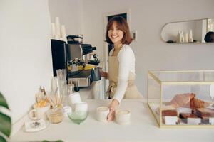 Beautiful female barista is looking at camera and smiling while working in coffee shop photo