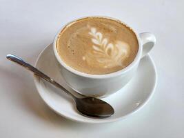 Coffee in a white cup on a white table. Cup and spoon photo