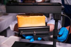 Melting and slicing raclette cheese using an electric melter photo