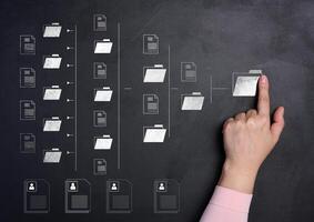 Female hand and folder over a black background with several folders and documents scattered around photo