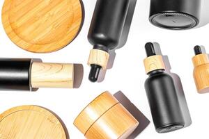 Set of cosmetic products in black and bamboo glass package. Beauty oil in dropper bottle and jars with cream for healthy skin. Unbranded package for cosmetics promotion. Knolling style, top view photo