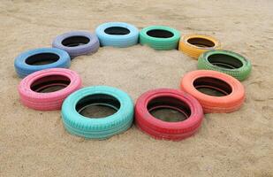Colorful tires on sand at playground photo