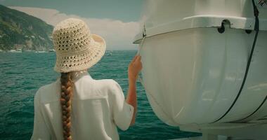 een glimlachen vrouw Holding een touw Aan een boot, met de zonovergoten kliffen van positano in de achtergrond. toerist genieten van zomer vakanties in Italië. video