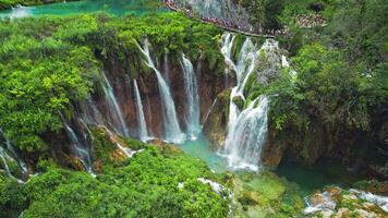 lång kö av människor vandring på smal väg i plitvice sjöar nationell parkera kroatien. berg landskap med strömmar av vatten och vattenfall. video