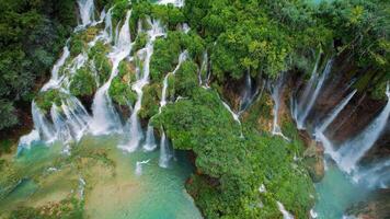 Alto cascata e rio córregos fluindo e queda abaixo. aéreo topo baixa Visão do exuberante verde penhasco dentro denso montanha floresta. Primavera água. video