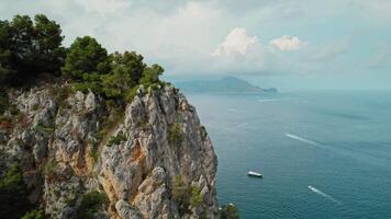 capri línea costera con maravilloso acantilados y lujo yates con turistas vela en el mar en Italia. el escarpado rocas torre terminado el océano. video