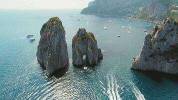 majestätisk hav stackar stiga från de blå vattnen av capri, Italien. fartyg flyta runt om naturlig sten formationer på de tyrrenska hav. video