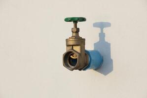 Water shut off valve installed on white wall with shadow. photo