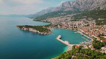 aérien vue de Makarska riviera dans Croatie. vibrant bleu mer des eaux bordé par le ville, avec majestueux montagnes en hausse dans le distance. video