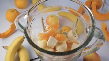 Fruit falling into a blender, super slow motion. Orange, banana, apple in a blender, top view. Healthy and vegetarian food concept video