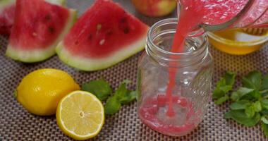 Watermelon banana Smoothie is poured into a jar on the background of fresh fruits. The fruit cocktail is ready to eat. Healthy and vegetarian food concept. Ultra 4K video