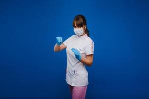 An attractive young female doctor holds a scalpel and looks directly at the camera. Concept of healthcare, treatment and surgery. Portrait of a medical practitioner on a blue background photo
