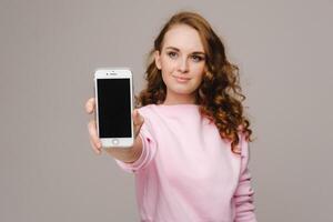 Fashionable girl with a smartphone on the background. Stands and shows the smartphone photo