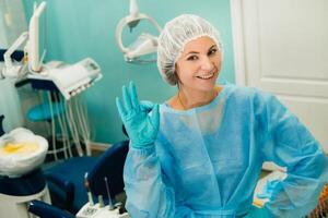 the dentist stands in his office and shows the OK sign photo