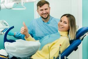 hermosa niña paciente muestra el clase con su mano mientras sentado en el del dentista silla foto