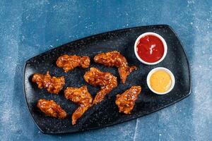 crispy chicken wings with ketchup and mayo dip served in dish isolated on background top view photo