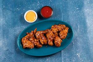 crispy chicken wings with ketchup and mayo dip served in dish isolated on background top view photo