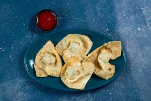 Crispy fried wonthon dim sum wraps with tomato sauce served in a dish isolaed on table top view photo