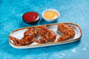 crispy chicken wings with ketchup and mayo dip served in dish isolated on background top view photo