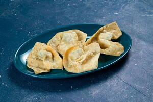 Crispy fried wonthon dim sum wraps with tomato sauce served in a dish isolaed on table top view photo