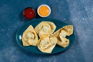 Crispy fried wonthon dim sum wraps with tomato sauce served in a dish isolaed on table top view photo