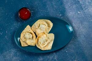 Crispy fried wonthon dim sum wraps with tomato sauce served in a dish isolaed on table top view photo