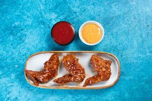 crispy chicken wings with ketchup and mayo dip served in dish isolated on background top view photo