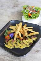Bistro Steak Frites with salad served in a dish isolated on grey background side view photo