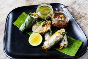 Fresh Spring Rolls with chilli sauce and lime served in a dish isolated on grey background side view of snacks photo