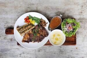 US Black Angus Rib Eye Steak with chilli sauce and salad served in a dish isolated on grey background side view photo