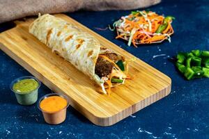 Beef Kofta shawarma Wrap with salad dip and sauce isolated wooden board side view of fastfood photo