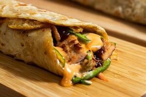 Egg Cheese Chicken Burger shawarma Wrap with salad dip and sauce isolated wooden board side view of fastfood photo