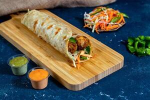 Beef Kofta shawarma Wrap with salad dip and sauce isolated wooden board side view of fastfood photo