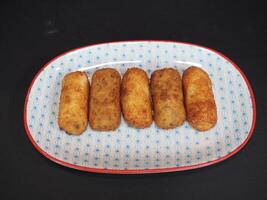 Ham and Mushroom Croquettes served in a dish isolated on dark background top view photo