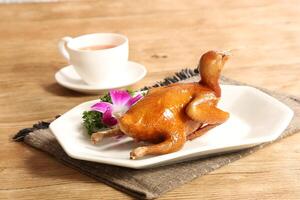 Traditional Cantonese grilled squab or pigeon in a dish isolated on grey background side view of Hong kong food photo