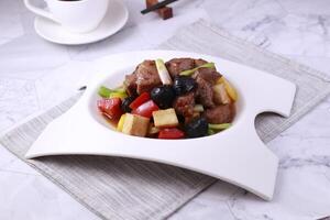 Black Garlic Mushroom and Beef Grain in a dish side view on grey background singapore food photo