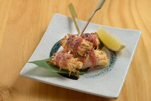 Crispy deep fried enoki mushrooms sticks on banana leaf on white plate isolated on wooden background top view photo