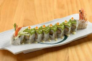 Sushi roll set green Dragon in white tray on wooden background top view photo