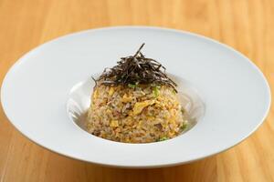 Garlic Chahan fried rice in white bowl on white plate isolated on wooden background top view of chinese food photo