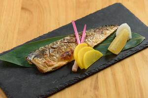 Japanese food grilled Saba fish Shioyaki with lime in a dish isolated on wooden background top view photo