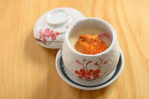 japanese cuisine Uni Chawanmushi in tea bowl isolated on wooden background top view photo