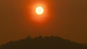 Zeit Ablauf von das Sonne Rahmen Über Hügel Das sind bedeckt mit Wolken, im das Stil von rauchig Hintergrund. video