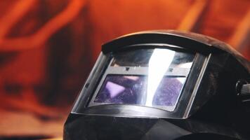 A welder's mask lies on a workbench in a dark home workshop. No one. Pan video