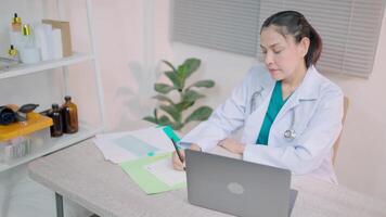 profissional médico escreve notas dentro uma caderno trabalhando com uma computador portátil em a mesa geral prática conceitos providenciar médico Cuidado conectados video