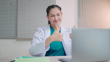 A female doctor chats live on a laptop computer during an online clinic visit to help see patients in a digital telehealth examination. video