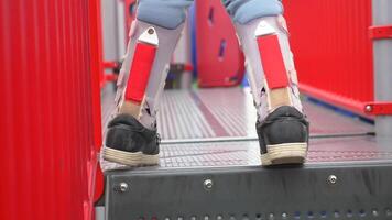 un pequeño niña en ortesis Zapatos cruces un de madera puente niño cerebral parálisis discapacidad. video