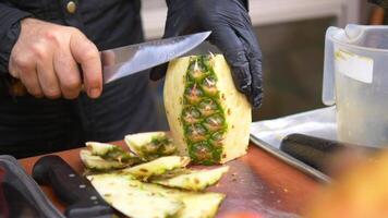 hand in gloves cutting slice of pineapple with knife video