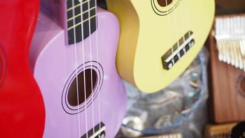 Purple and yellow ukuleles resting on table, both string instruments video